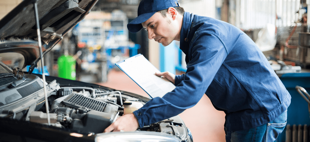Car Mechanic looking at a vehicles bonnet and checking the engine oil - Servicing & Repairs